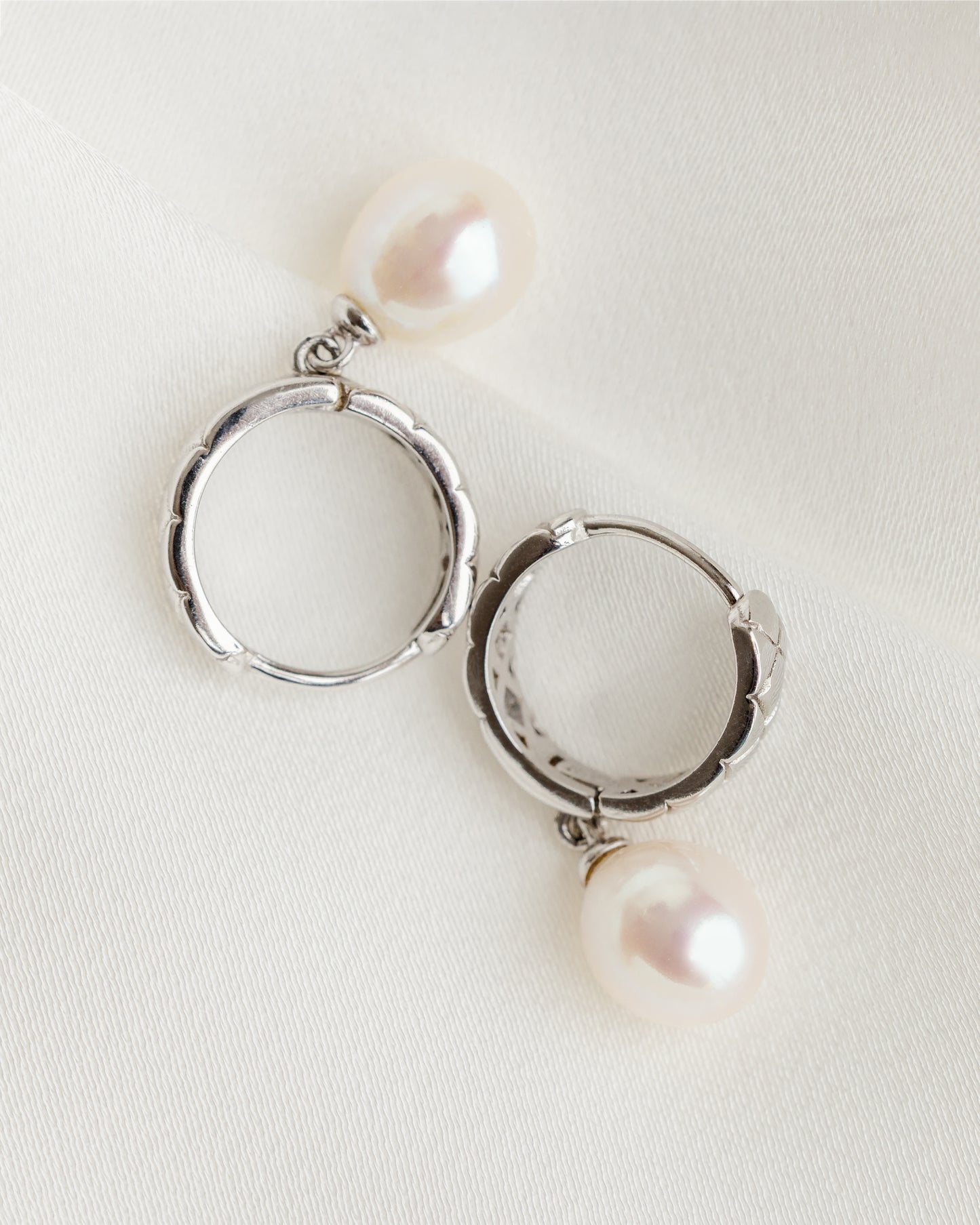 Silver hoop earrings with pearls on a light background