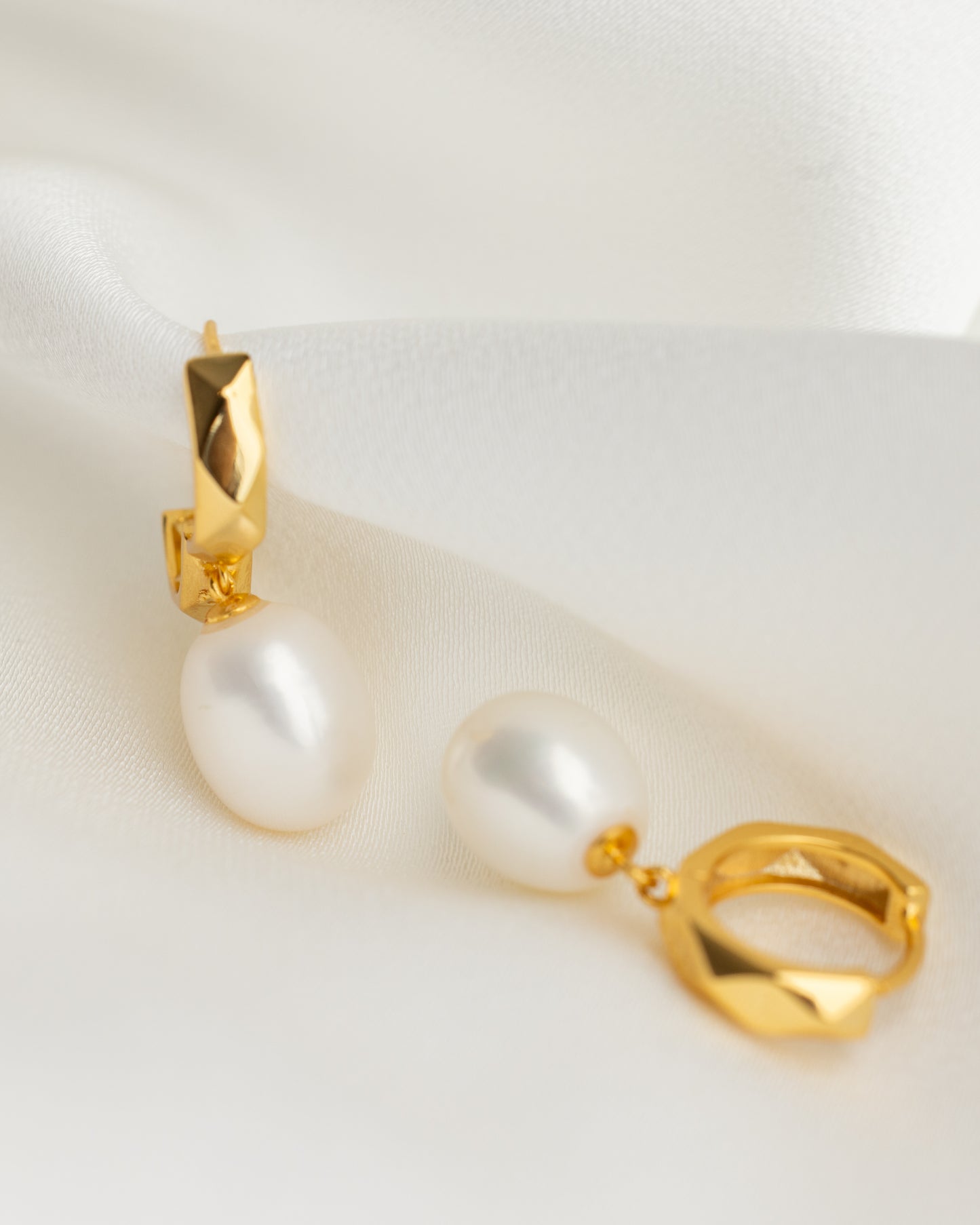 Gold earrings with pearl-like beads on a white background