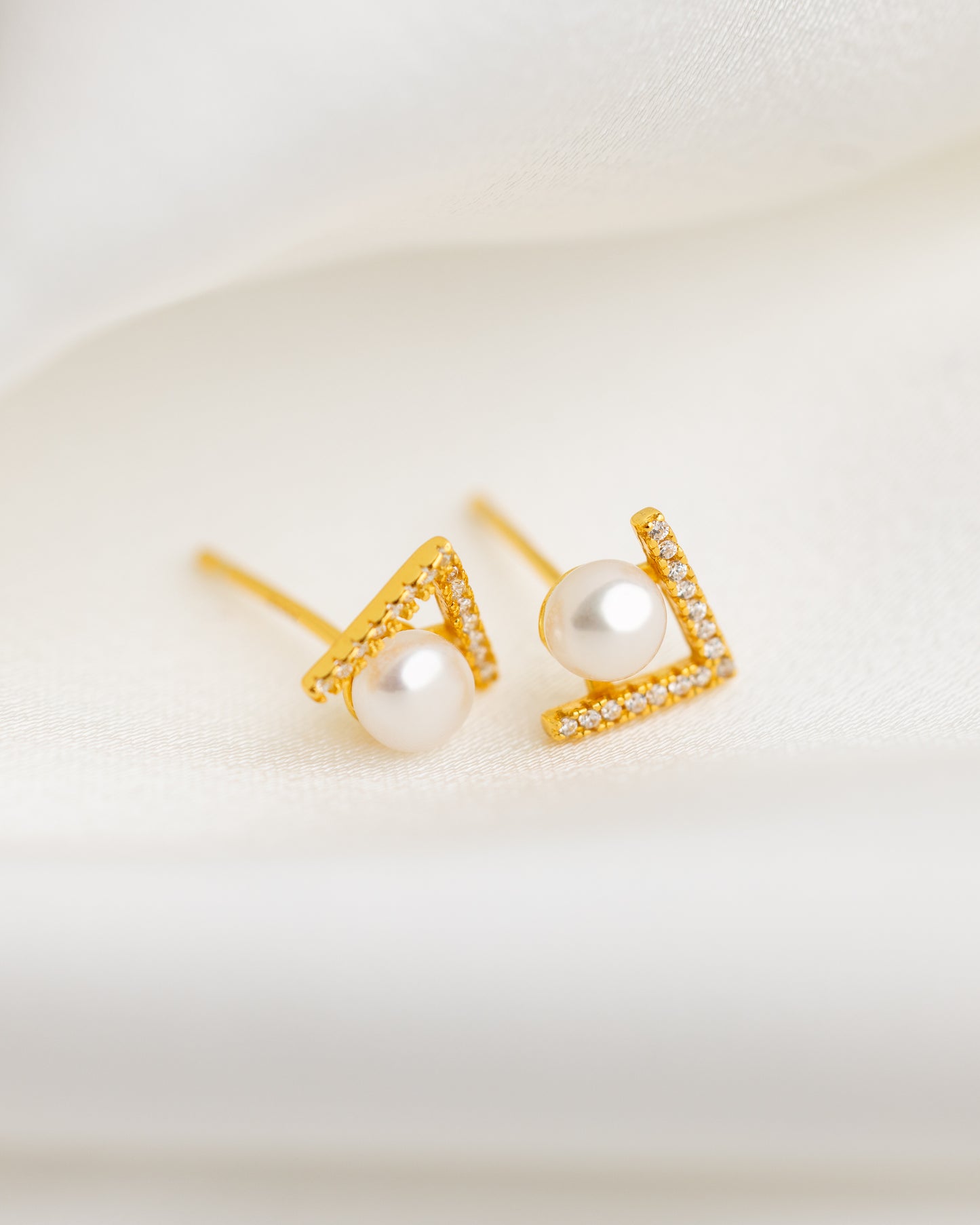 Gold earrings with pearl centers on a light background