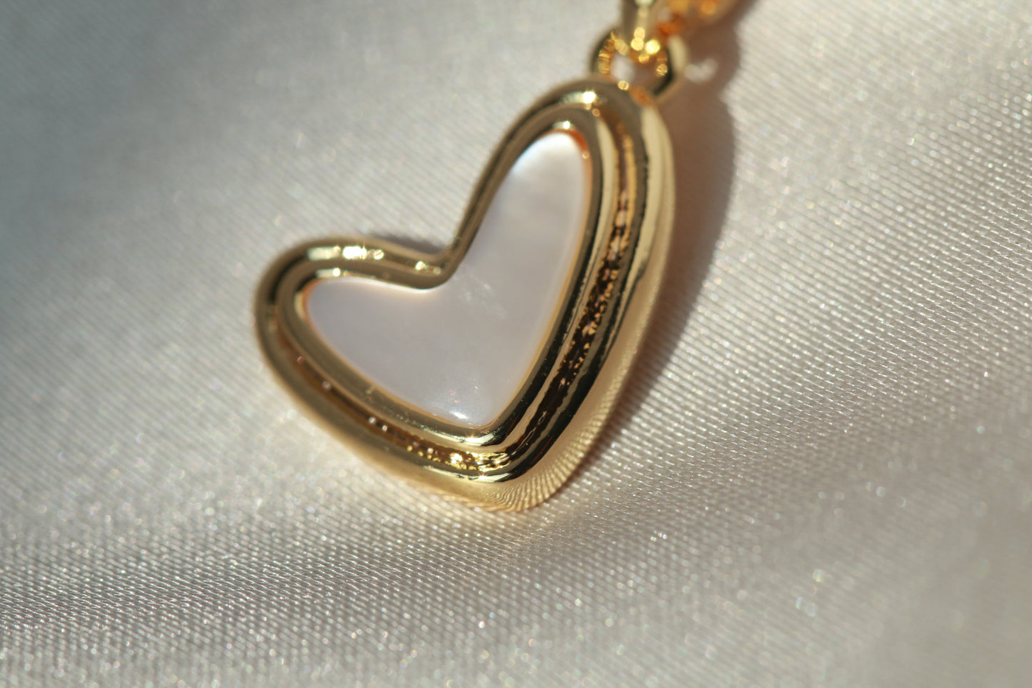 Gold heart-shaped pendant on a light fabric background
