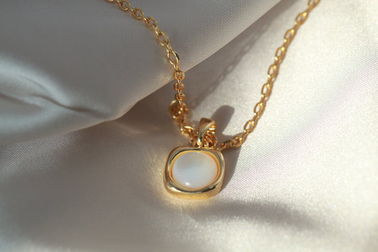 Gold necklace with a pendant on a white fabric background