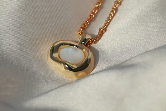 Gold necklace with a heart-shaped pendant on a light fabric background