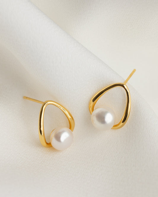 Gold earrings with pearls on a light background