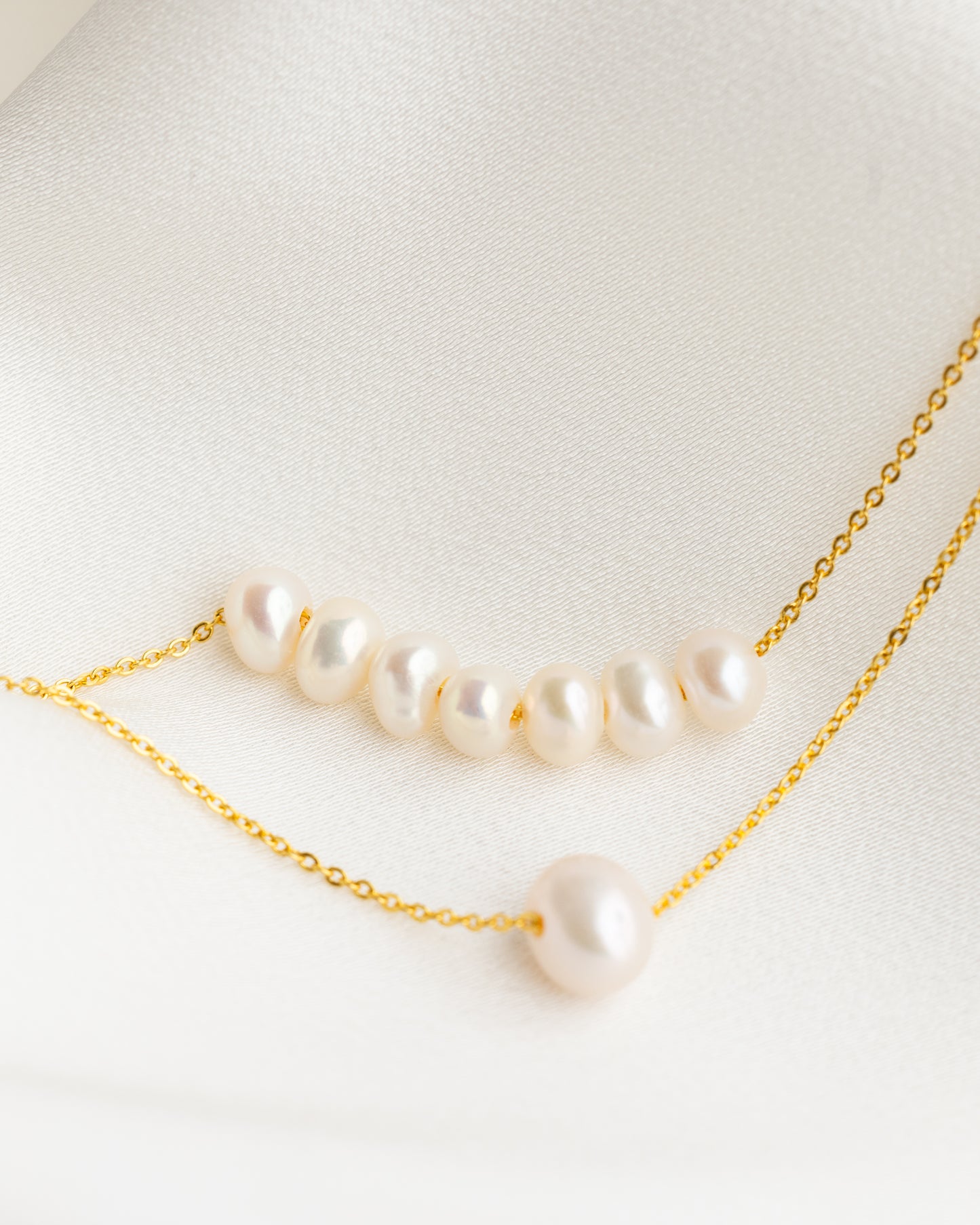 Pearl necklace with gold chain on a light background