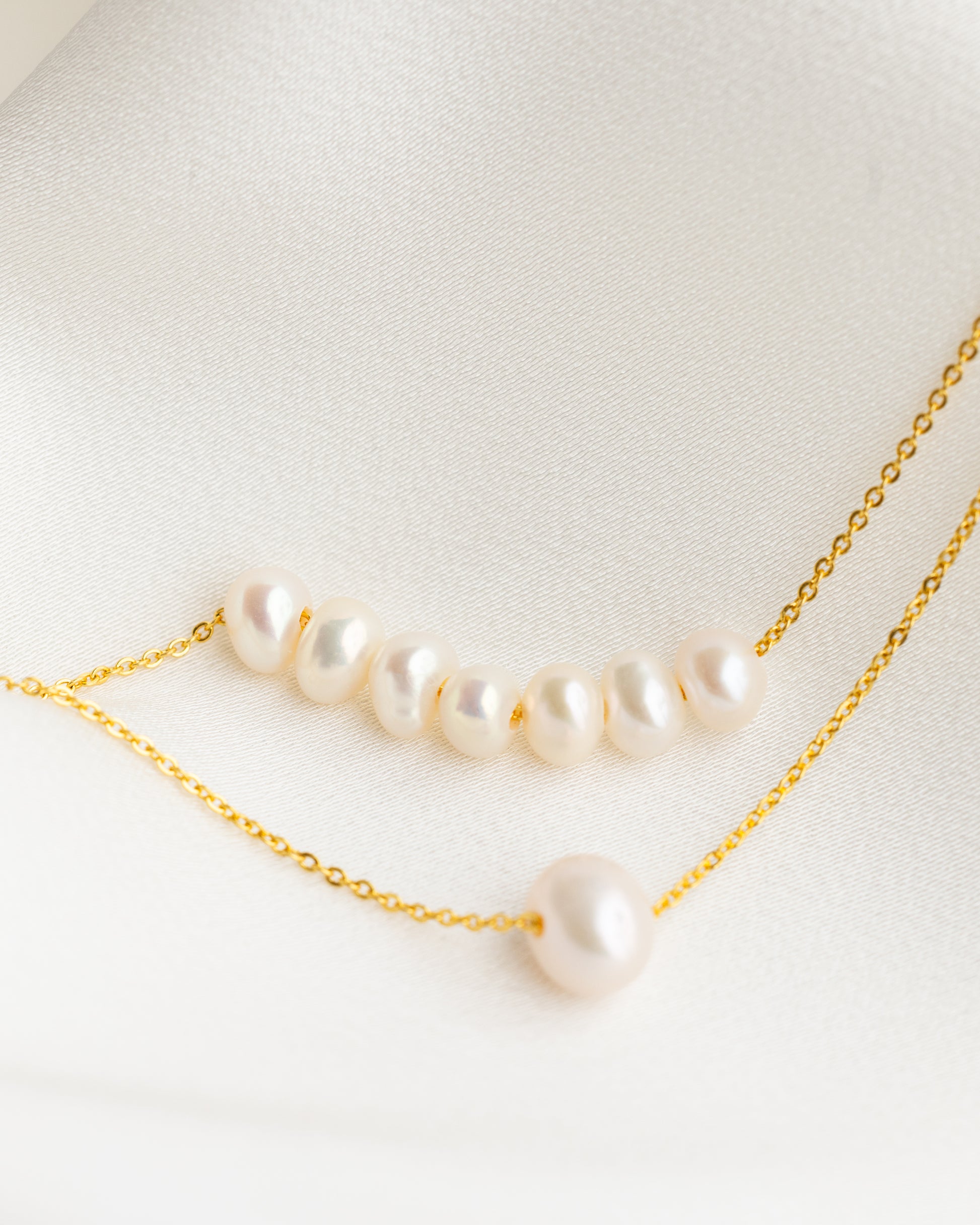 Pearl necklace with gold chain on a light background