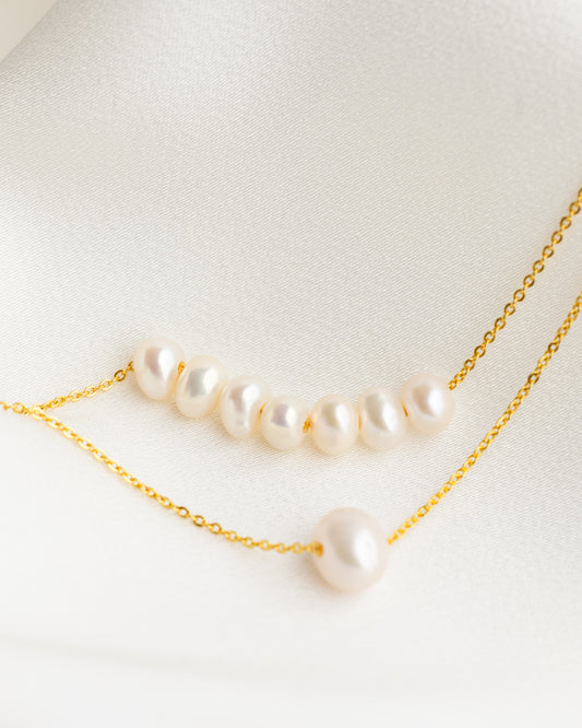 Pearl necklace with gold chain on a light background