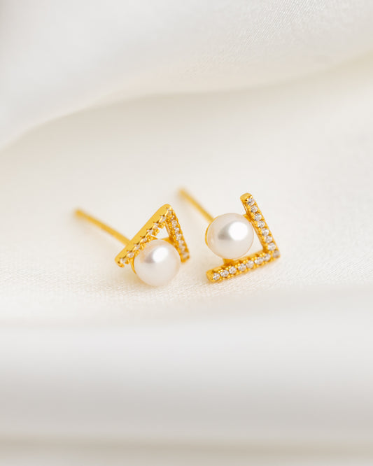 Gold earrings with pearl centers on a light background