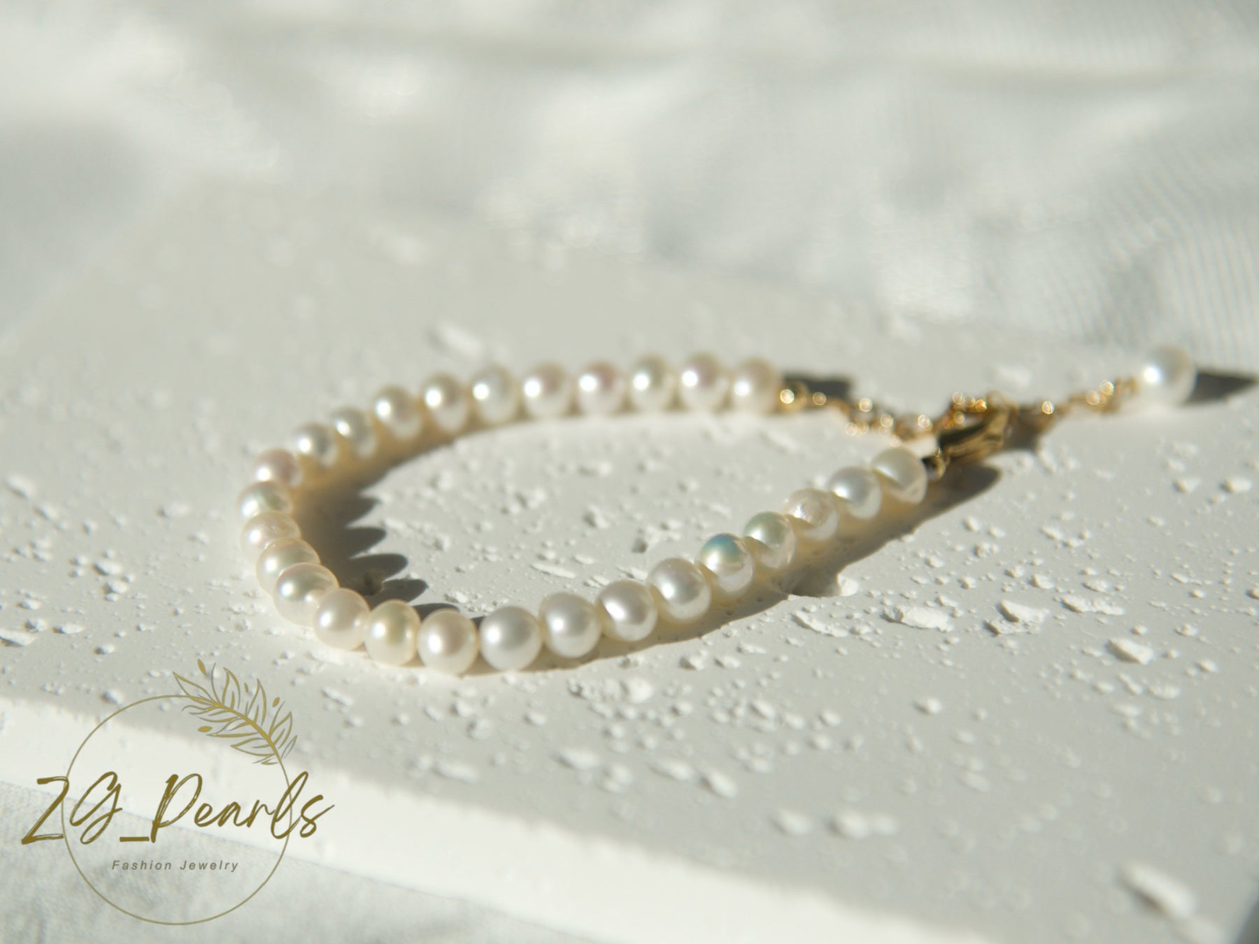 Pearl bracelet on a textured white surface with 'ZG Pearls' branding.