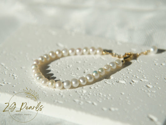 Pearl bracelet on a textured white surface with 'ZG Pearls' branding.