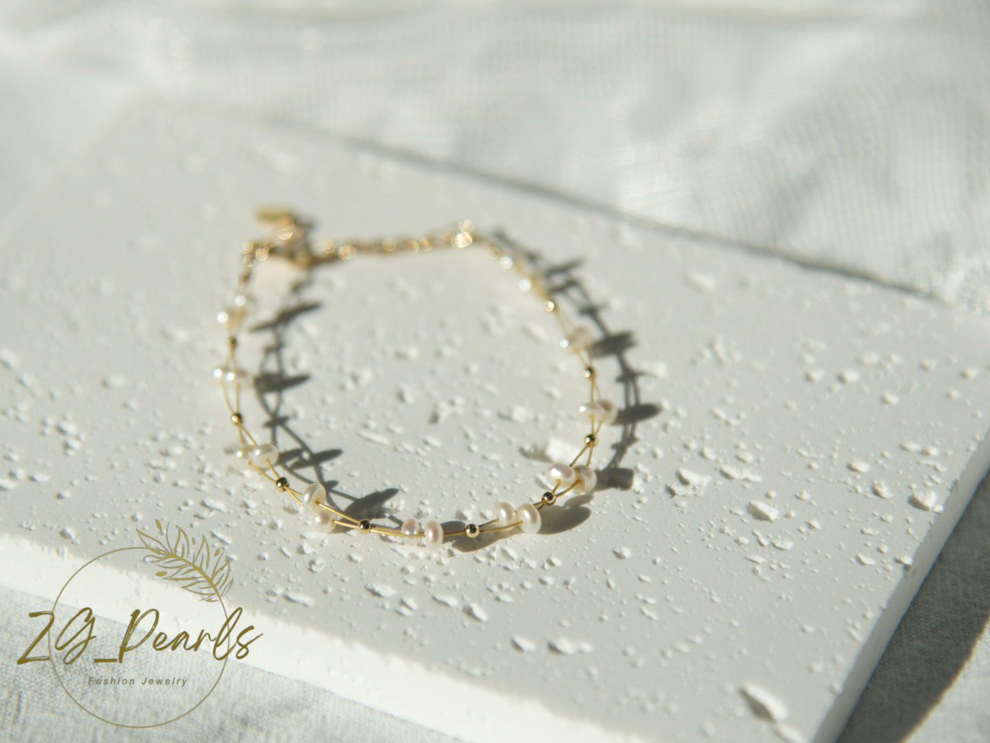 Gold bracelet with pearls on a light background, featuring the brand 'ZG Pearls'.
