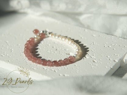 a pearl bracelet with pink strawberry crystal on a textured white surface with 'Zg Pearls' branding.