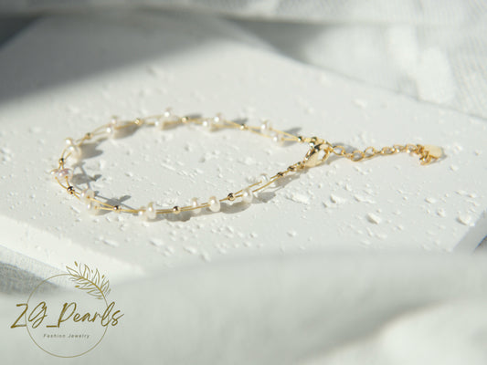 Gold and pearl bracelet on a white surface with 'ZG Pearls' branding.