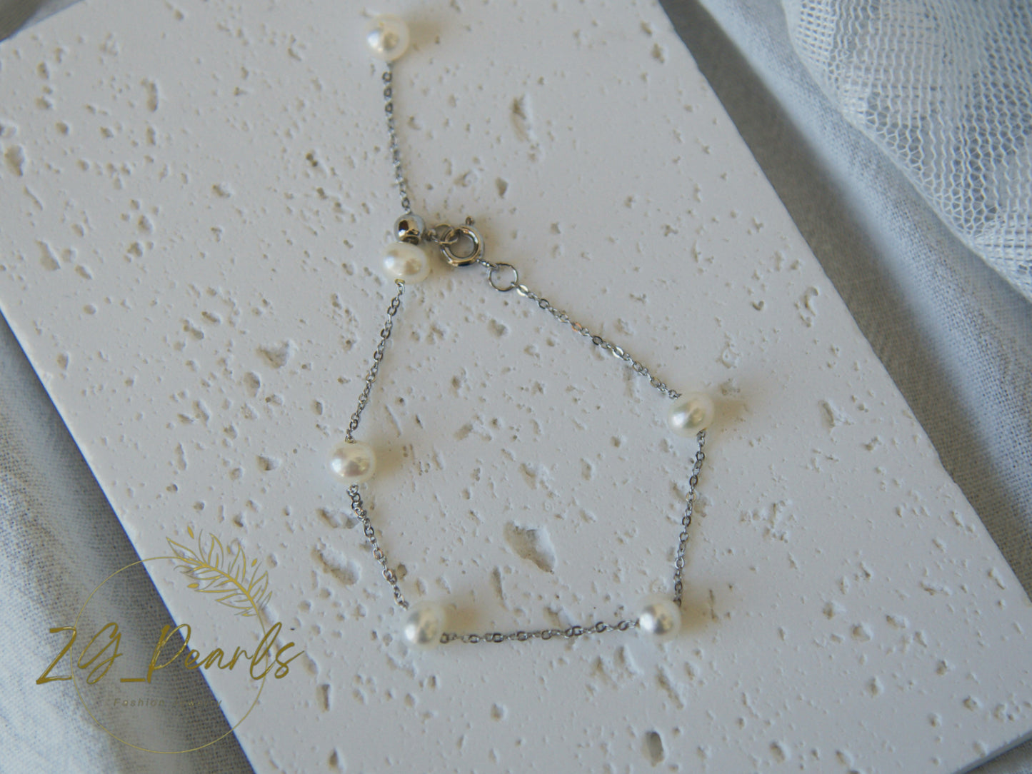 Pearl necklace on a textured white surface with '2g Pearls' branding.