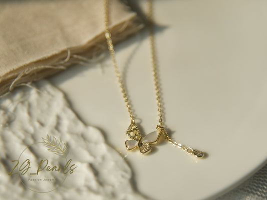Gold necklace with a pendant on a textured surface, featuring the brand 'ZG Pearls'.