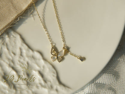 Gold necklace with heart-shaped pendant on a textured surface, featuring 'ZG Pearls' brand.