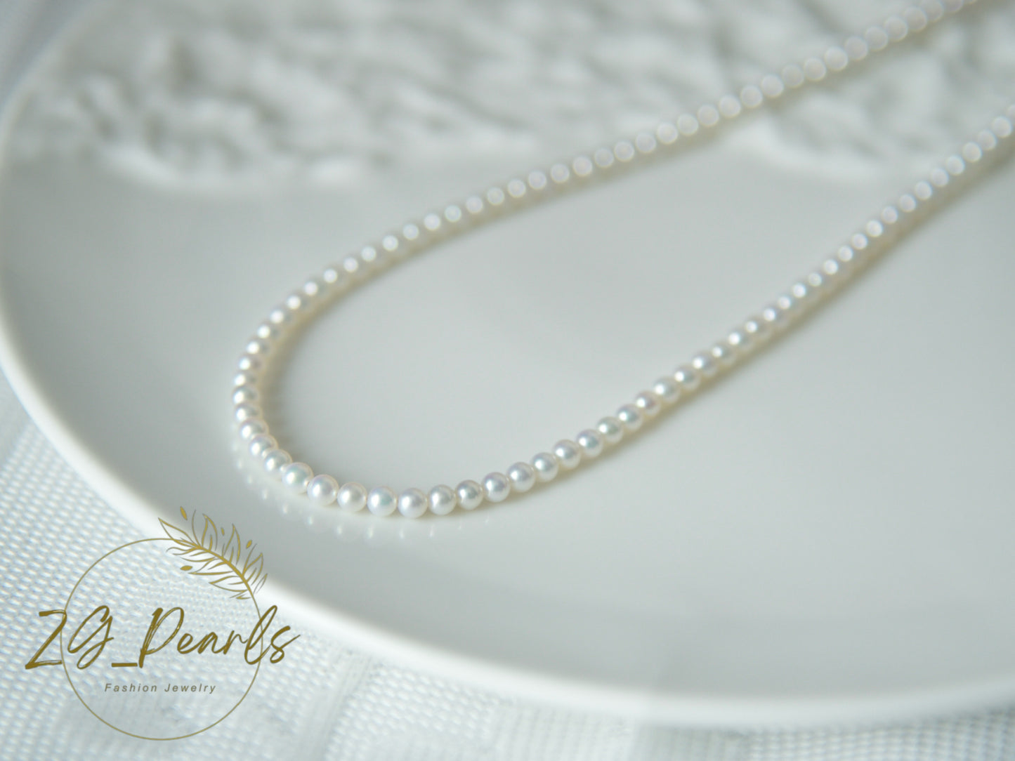 Pearl necklace on a textured white surface with 'ZG Pearls' branding.