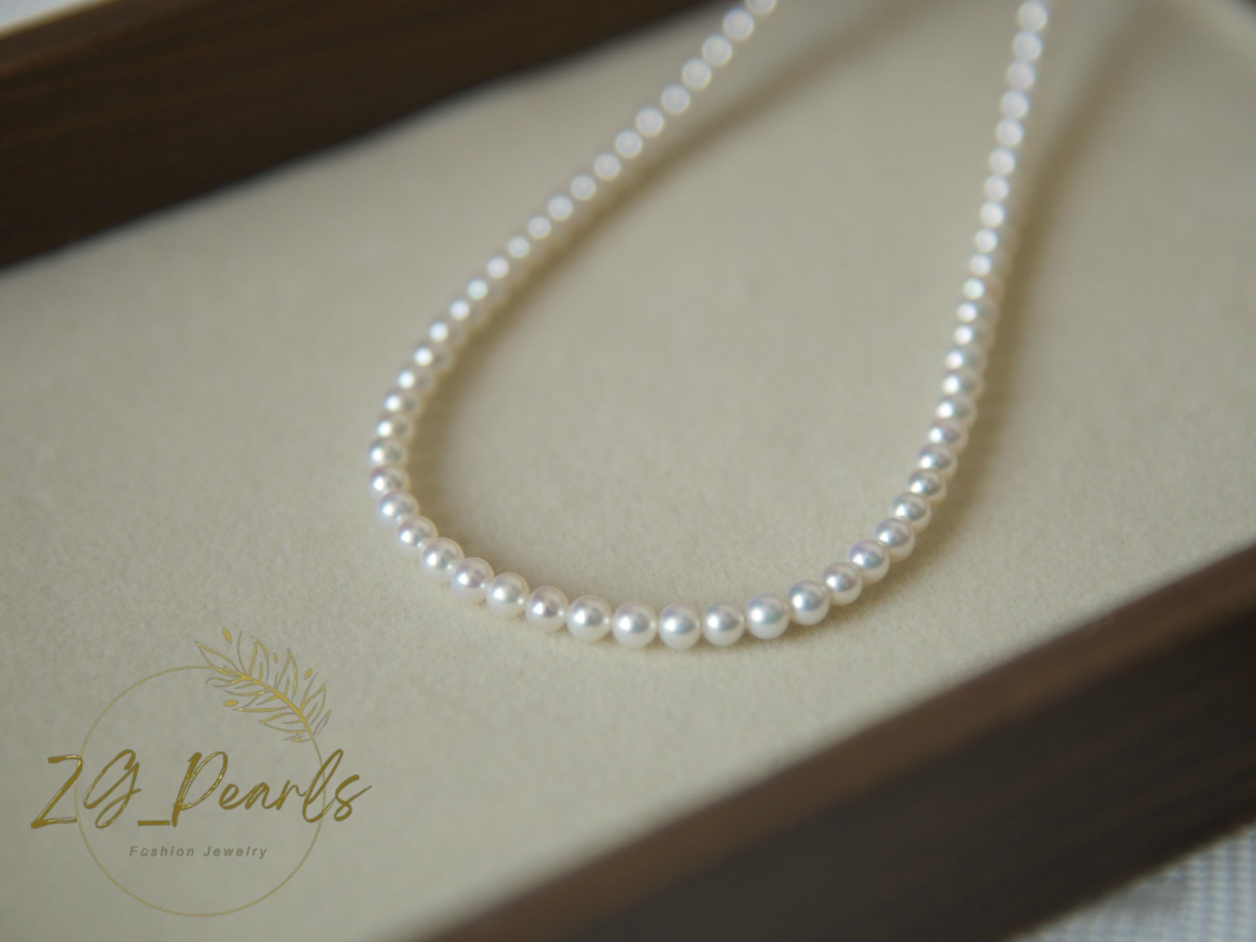 Pearl necklace on a beige surface with 'ZG Pearls' branding.