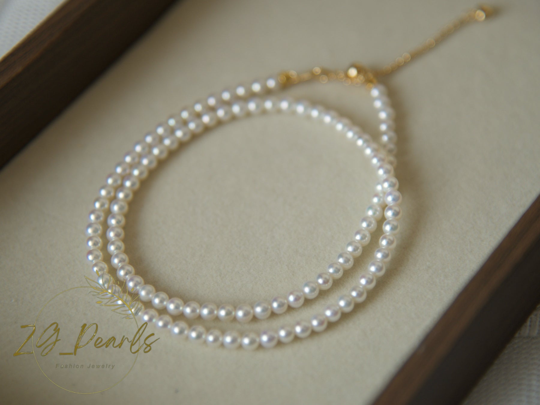 Pearl necklace on a beige surface with 'ZG Pearls' branding.