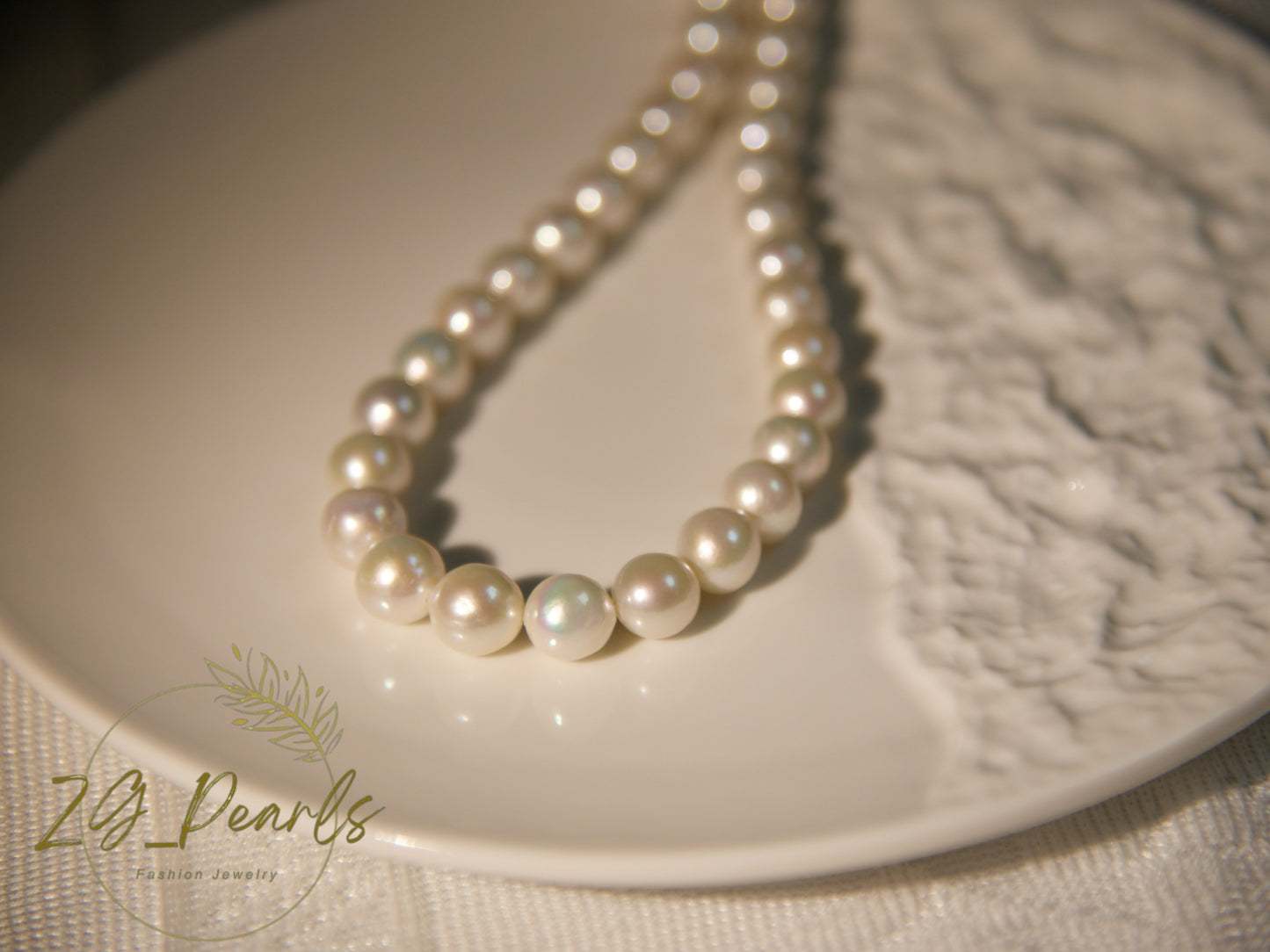 Pearl necklace on a textured white surface with 'ZG Pearls' branding.