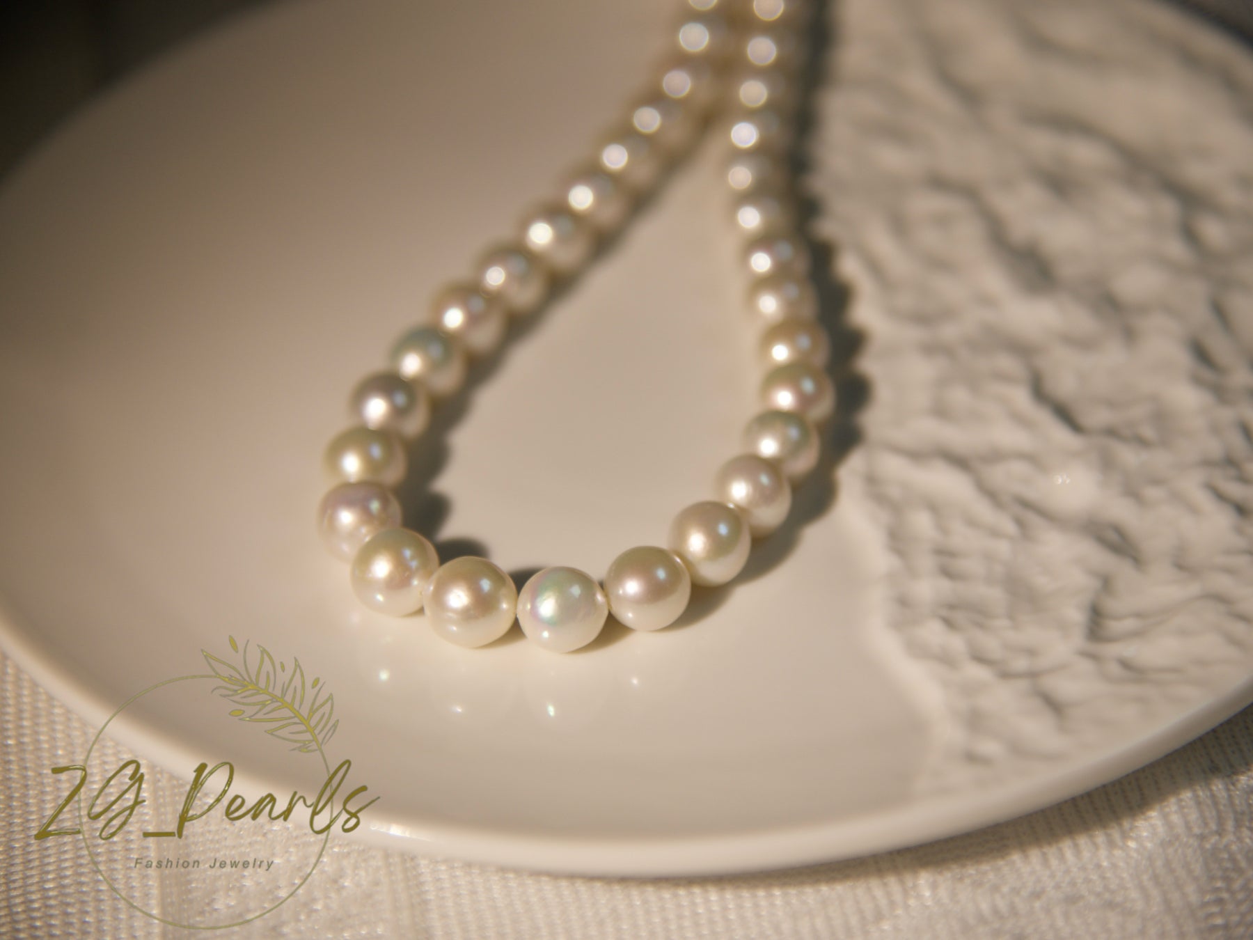 Pearl necklace on a textured white surface with 'ZG Pearls' branding.