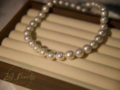 Pearl necklace on a wooden stand with 'ZG Pearls' branding.