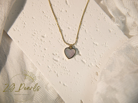 Necklace with a heart-shaped pendant on a textured beige background, featuring the brand 'ZB Pearls'.