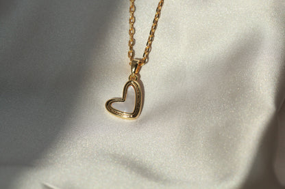 Gold heart-shaped necklace on a light fabric background