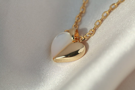 Gold necklace with a heart-shaped pendant on a light fabric background